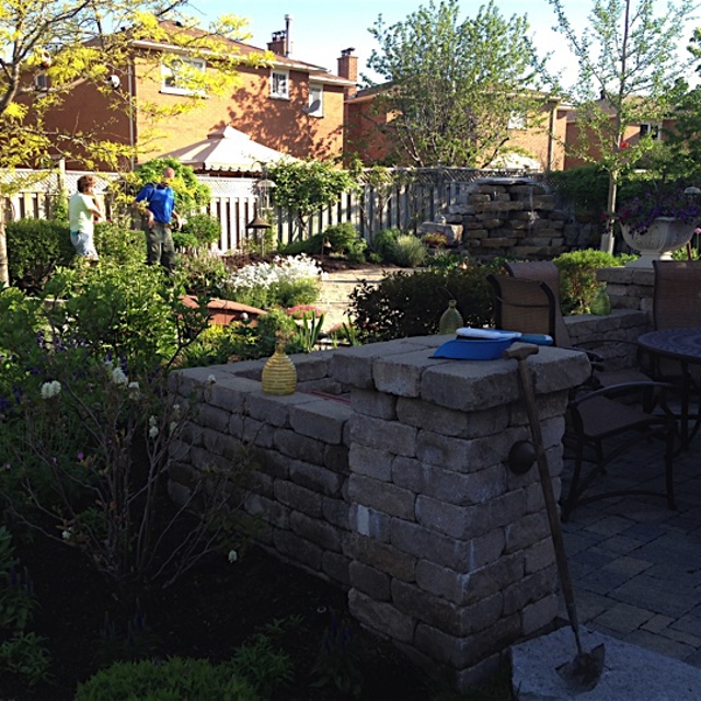A Ground guy speaking to the owner of a garden with stone pavements and stone sculptures.