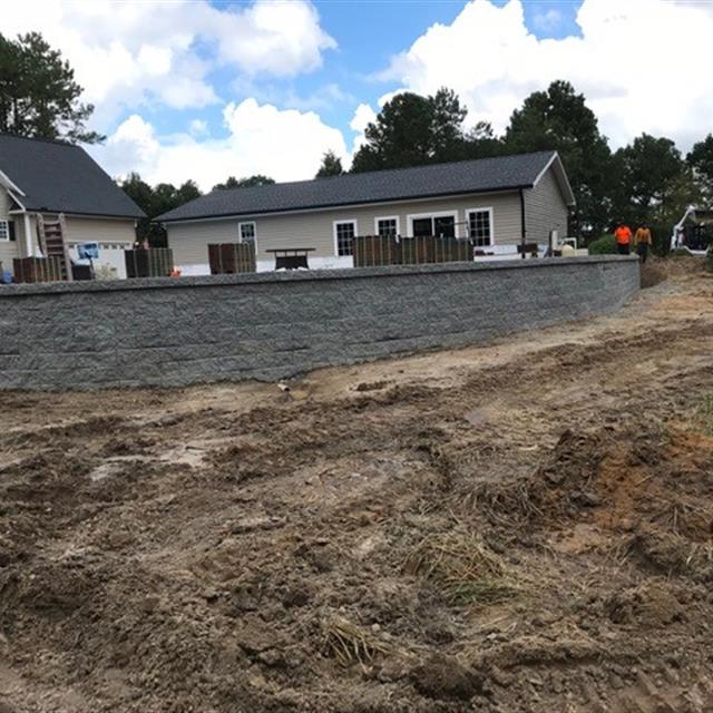 A side view of landscaping work underway in front of a house.