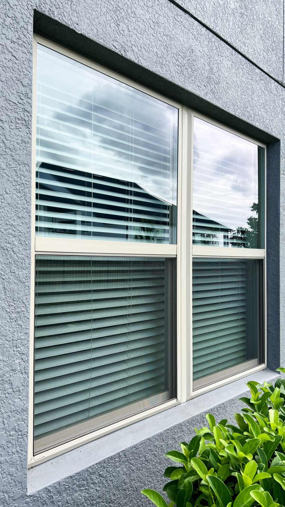 a clean window mounted on a blue stucco wall.