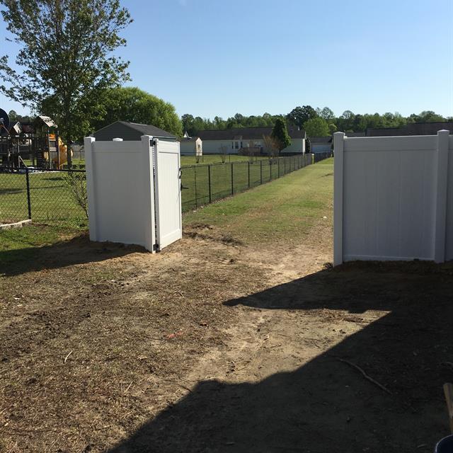 An opened white fence with a gate.