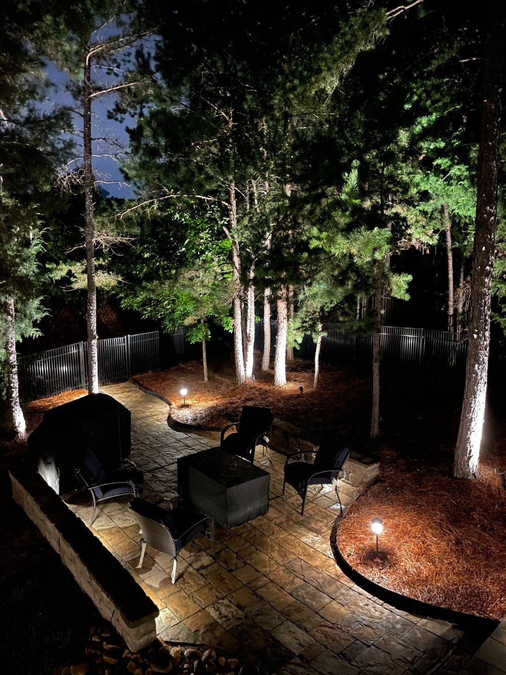 Backyard patio pathway and stone wall paver lighting illuminates a wonderful gathering area.