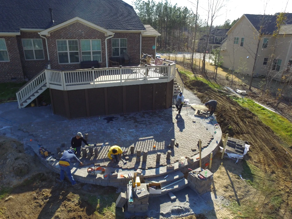 Brick home with patio and men laying cement in a circular patio formation