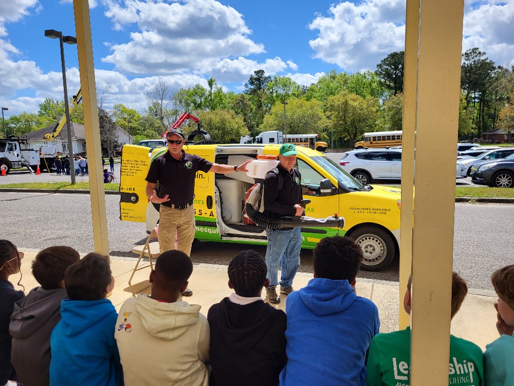 Two Mosquito Joe employees teaching elementary school kids about pest control careers.