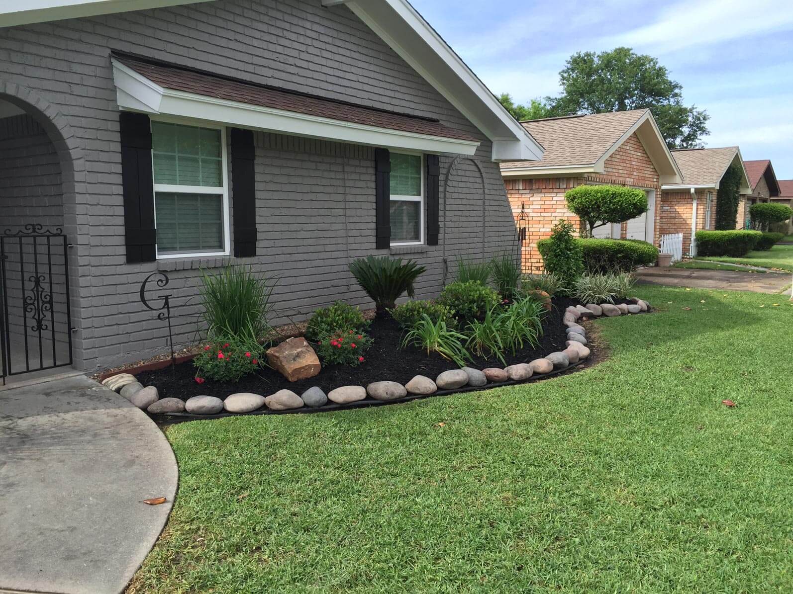 Front of grey house with plants in front of window