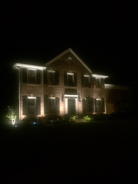 House at night lit by landscape outdoor lights.