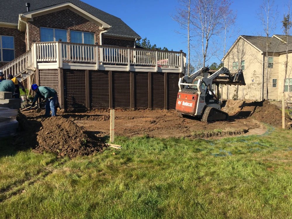 Large brick home with backhoe clearing yard