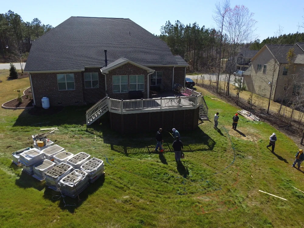 Large brick home with patio and yard workers