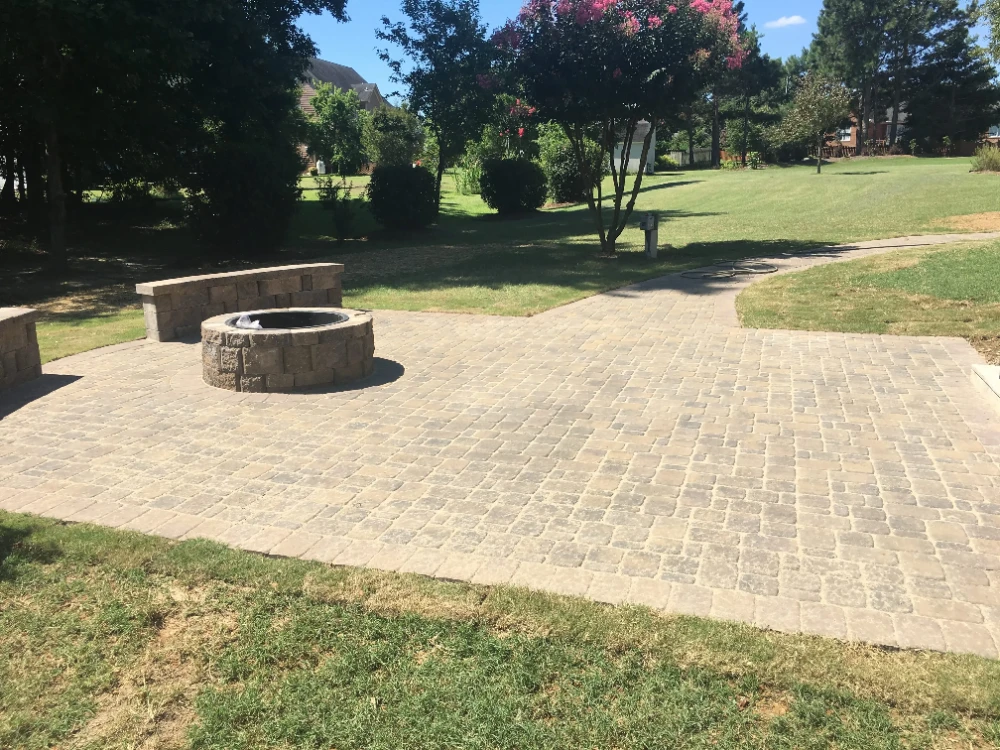 Large yard with completed brick pathway and fire pit in the sunlight