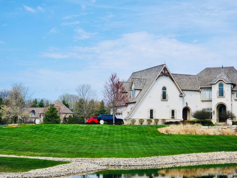 Lakefront residential property with well-maintained turf, clean lawn contours, and decorative landscape edging in McHenry County, IL, professionally serviced by a Libertyville landscaping company