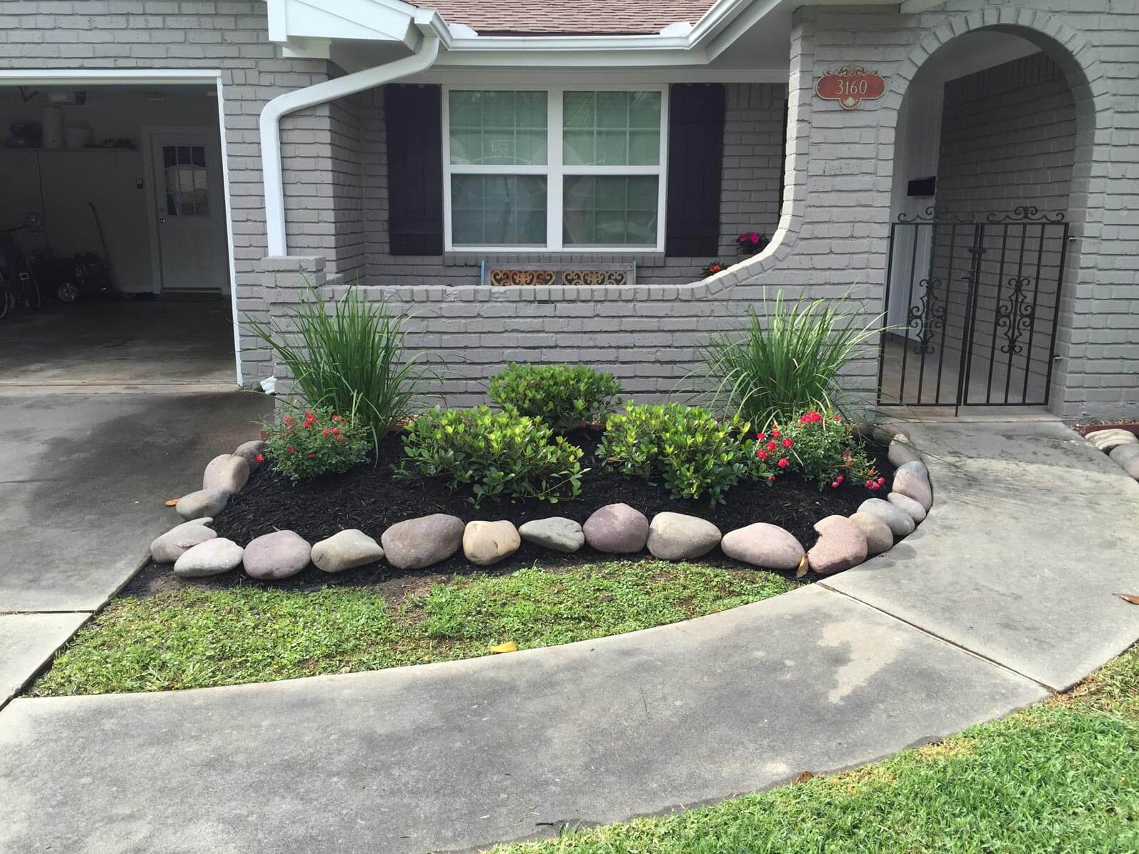 Soil and stone landscape in front of grey house