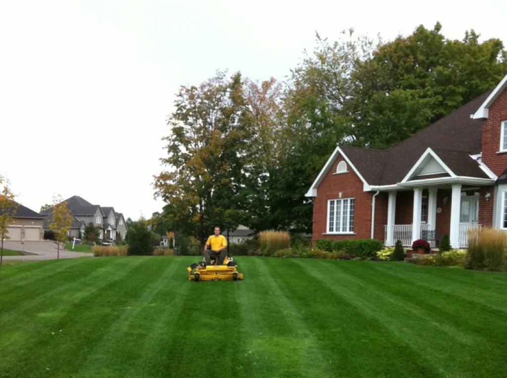 The Grounds Guys employee mowing a General lawn