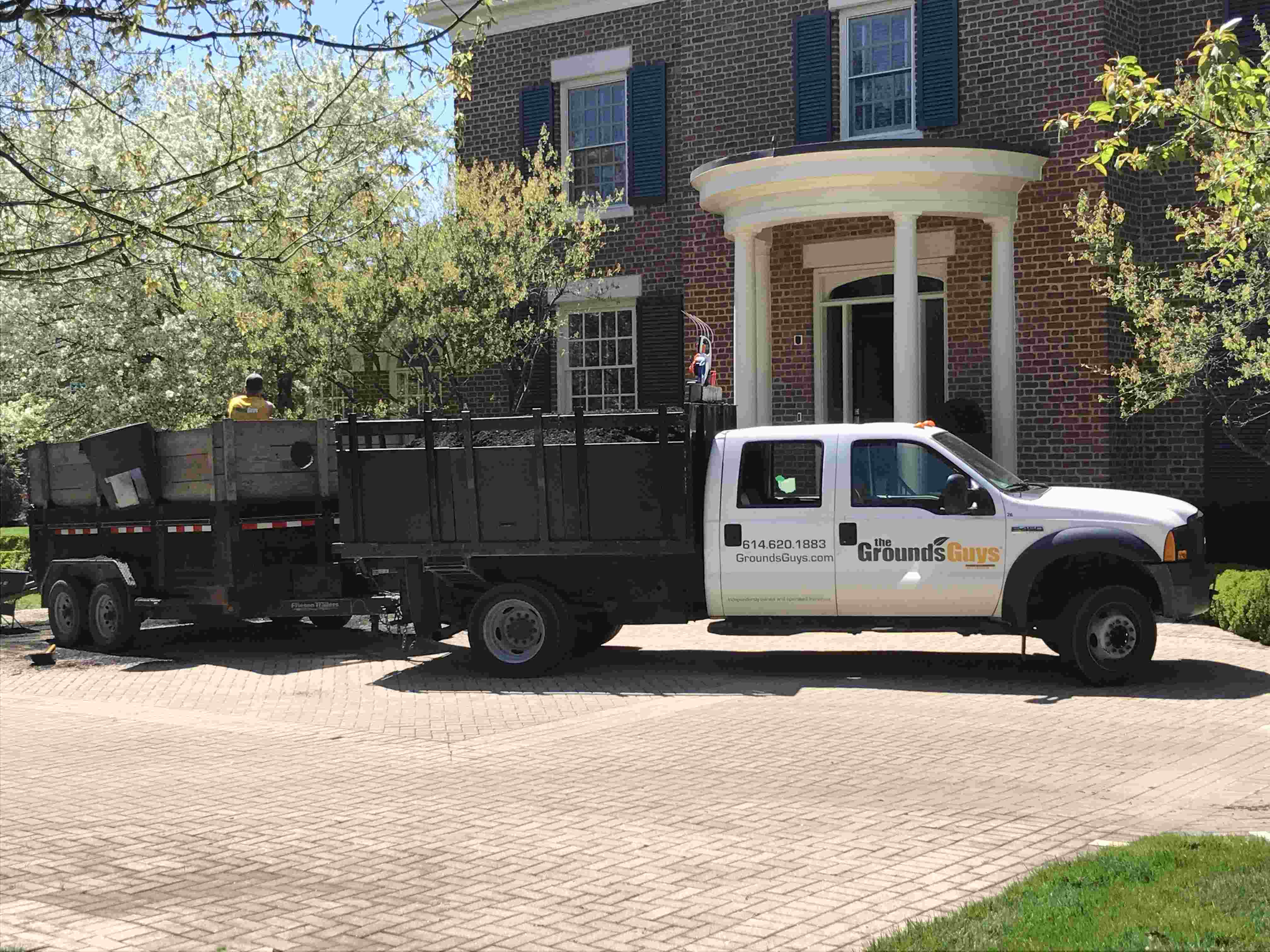 The Grounds Guys truck in front of brick house