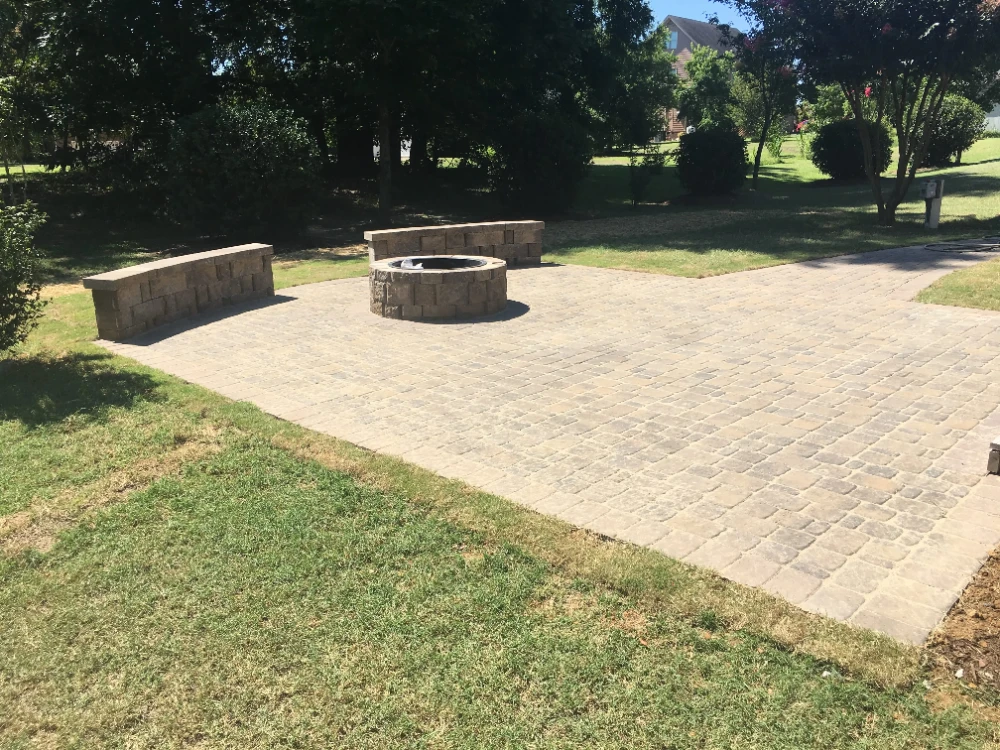 View of completed brick patio with fire pit in back yard
