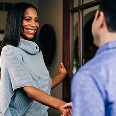 Customer greeting and shaking hands with Window Genie service professional at the door.