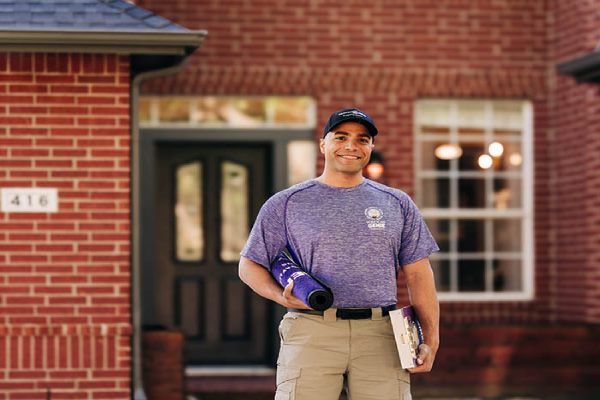 Window Genie technician standing in front of a brick home and smiling