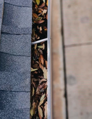 A leaf-filled gutter in need of cleaning at a commercial property
