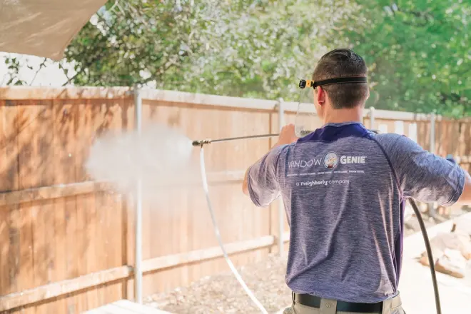 Window Genie professional power washing a wooden fence.