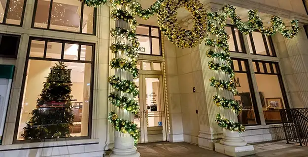 A storefront of a commercial building lavishly decorated with holiday lights and garlands.