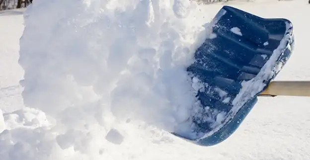 Snow being tossed with a large shovel.