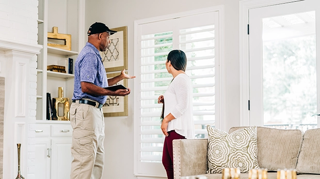 Window Genie service professional in customer's living room discussing windows.