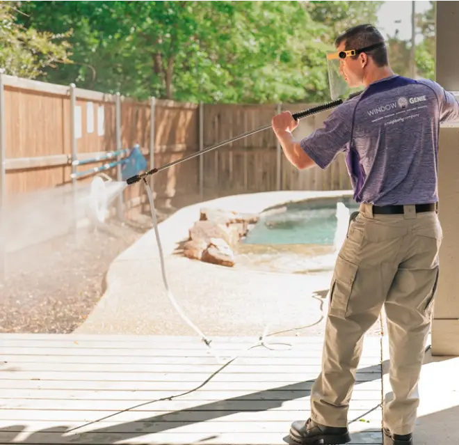 Window Genie service professional pressure washing a fence in a backyard.