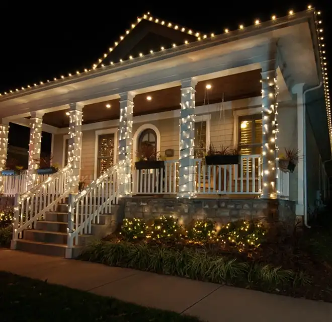 Window Genie service professional hanging holiday lights along a home's gutters.