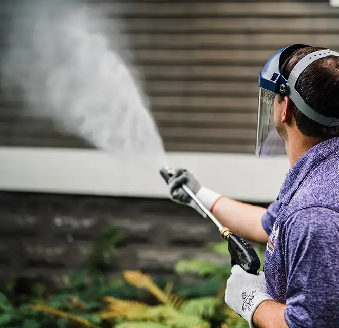 Window Genie service professional power washing the siding of a building.