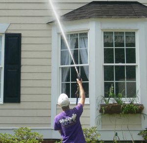 Window genie technician washing a house.