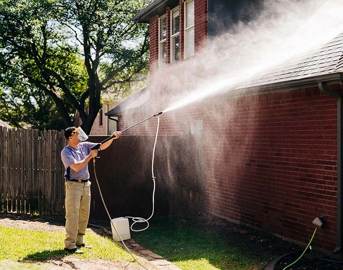 Window Genie service professional washing the roof of a single-family home.