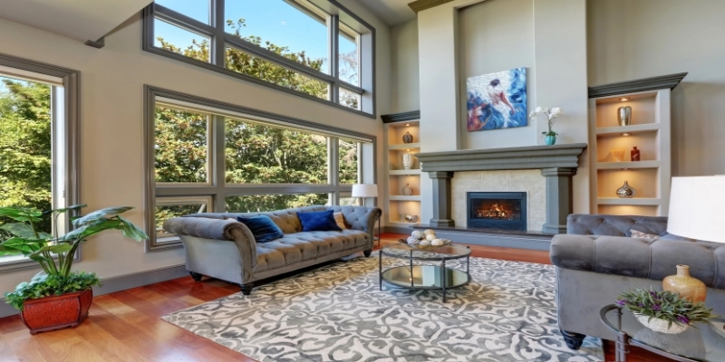 High vaulted ceiling family room in luxury house with fireplace and large windows.