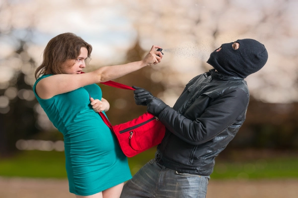 Self defence concept young woman is spraying with pepper spray on thief.