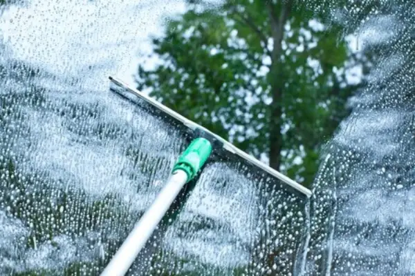 Cleaning outside window with squeegee.