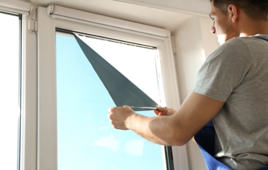 Technician installing a window film over an existing window.
