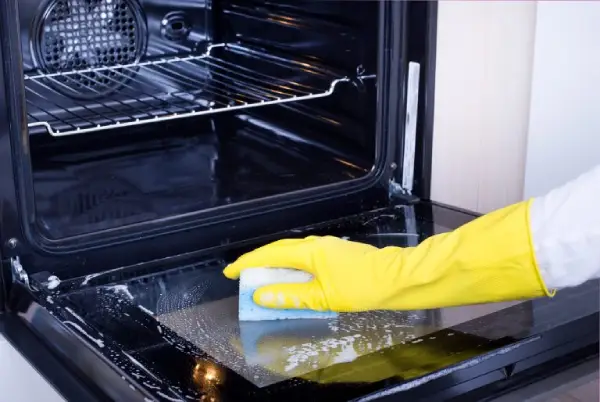 hand cleaning inside of oven door.